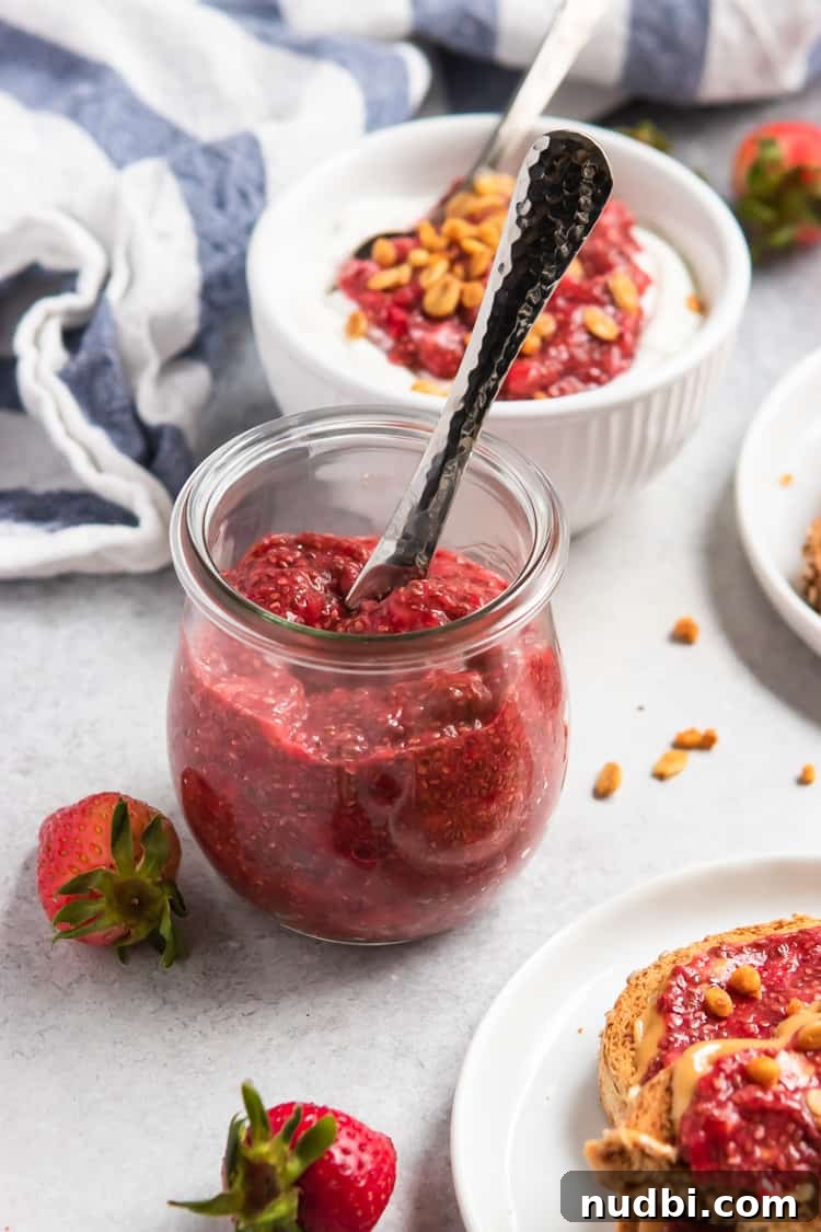 Jar of vegan chia seed jam with knife and berries beside it.