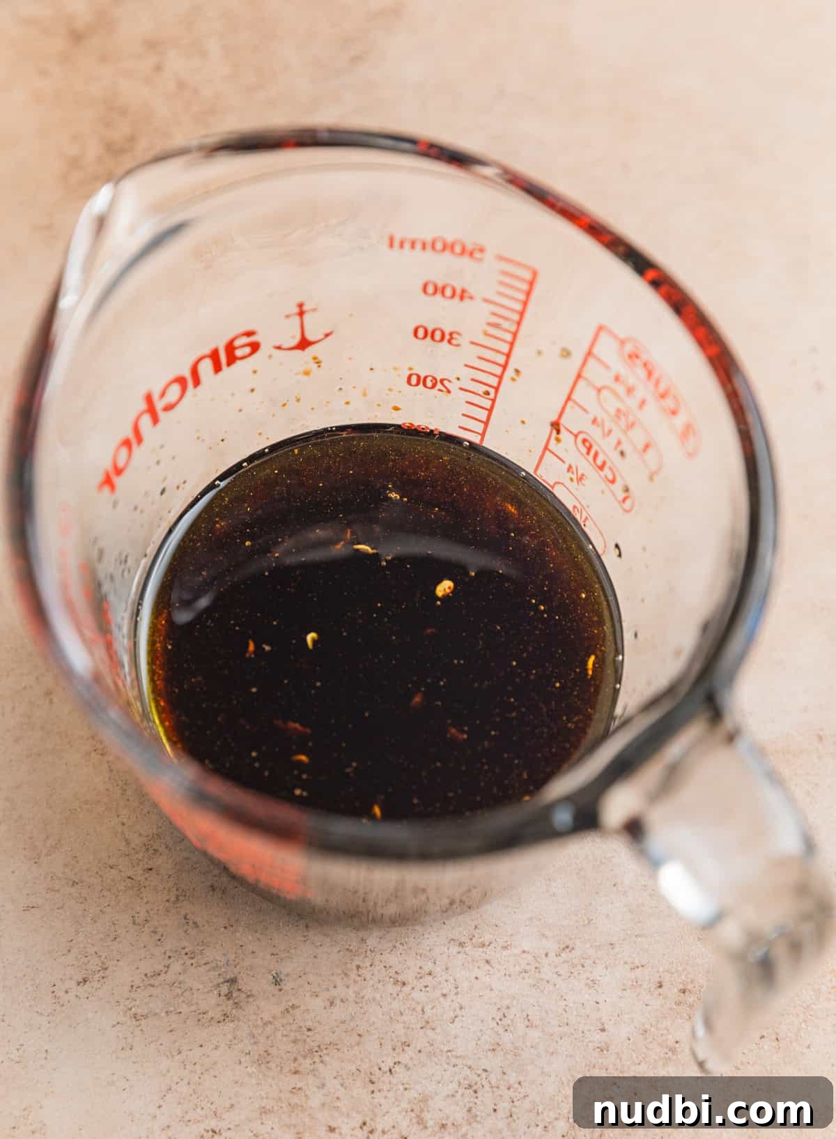 Olive oil, balsamic vinegar, garlic, salt and pepper mixed in measuring cup.