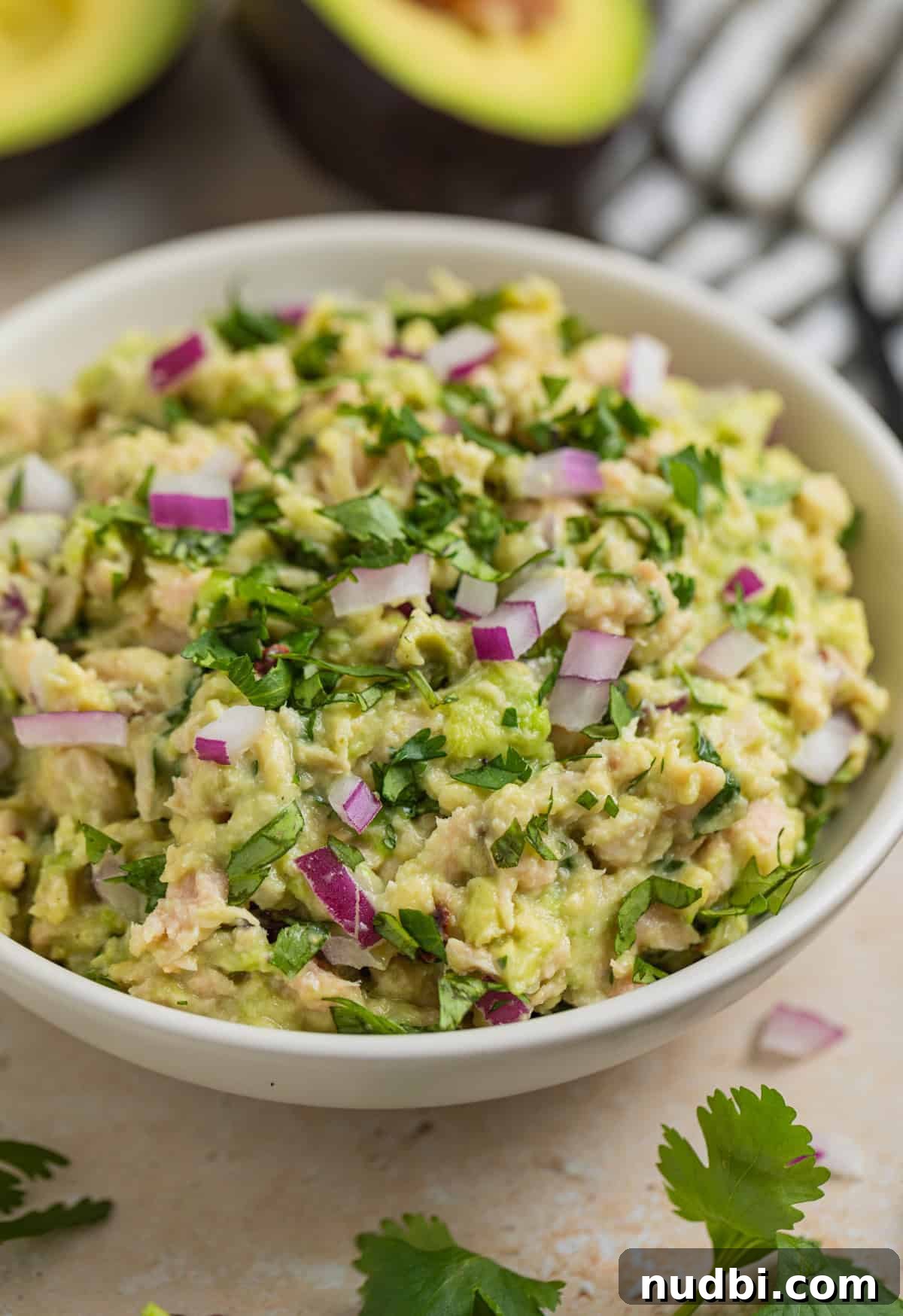 Creamy Avocado Ranch Tuna Salad with Fresh Herbs 2 Avocado tuna salad in bowl topped with chopped cilantro and diced red onion.