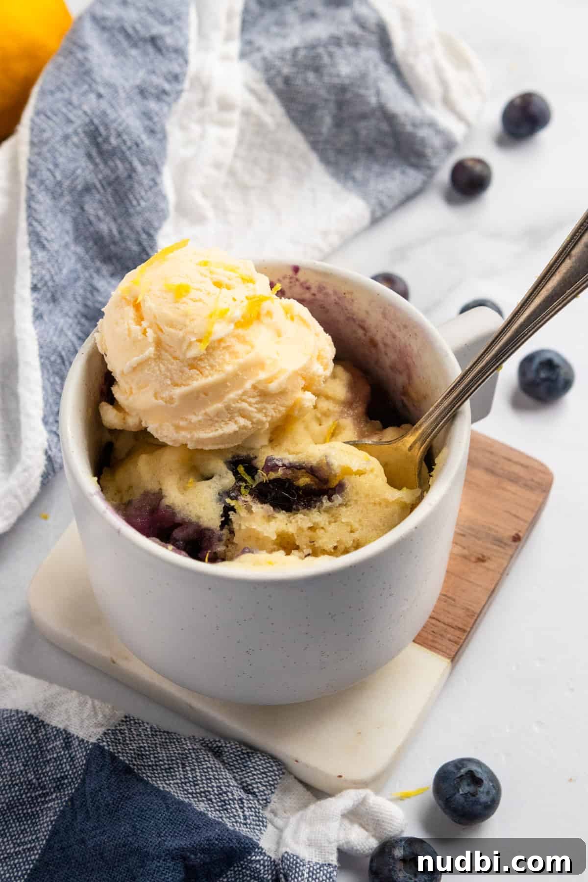 Blueberry Lemon Mug Cake Recipe — Ready in Minutes 2 Lemon mug cake in white mug with ice cream on top.
