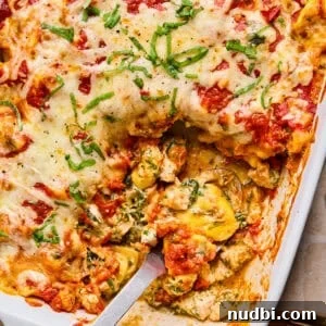 Creamy Spinach and Ricotta Tortellini Bake 16 Casserole dish with baked cheesy tortellini with serving spoon scooping into it.