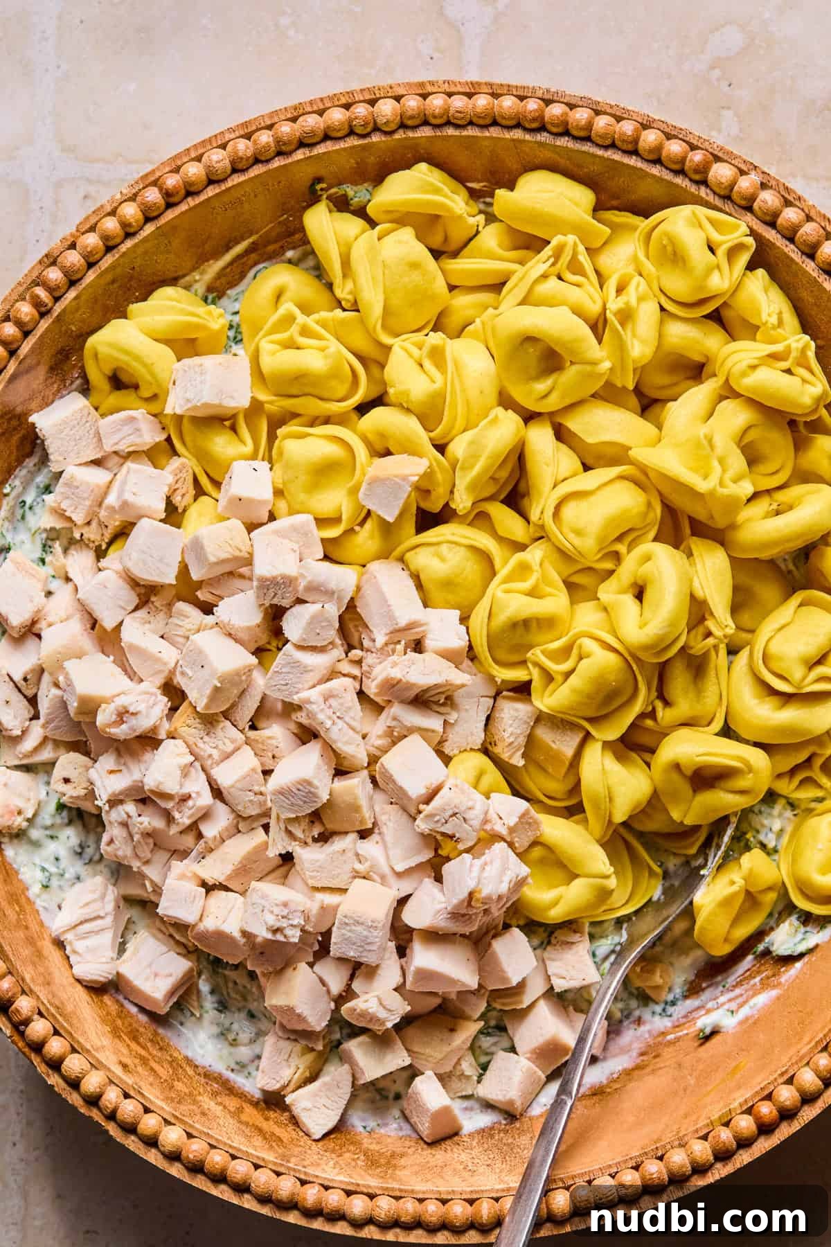 Creamy Spinach and Ricotta Tortellini Bake 7 Tortellini and cubed chicken in mixing bowl with cheese mixture.