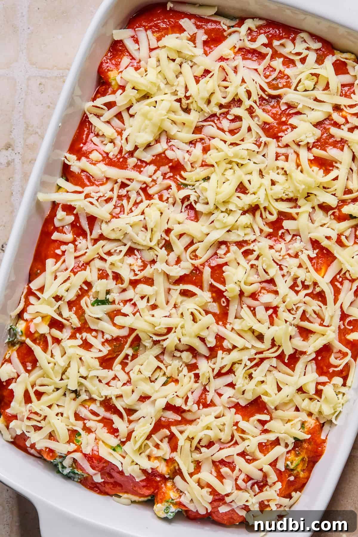 Creamy Spinach and Ricotta Tortellini Bake 9 Cheese covering marinara in pan with pasta.