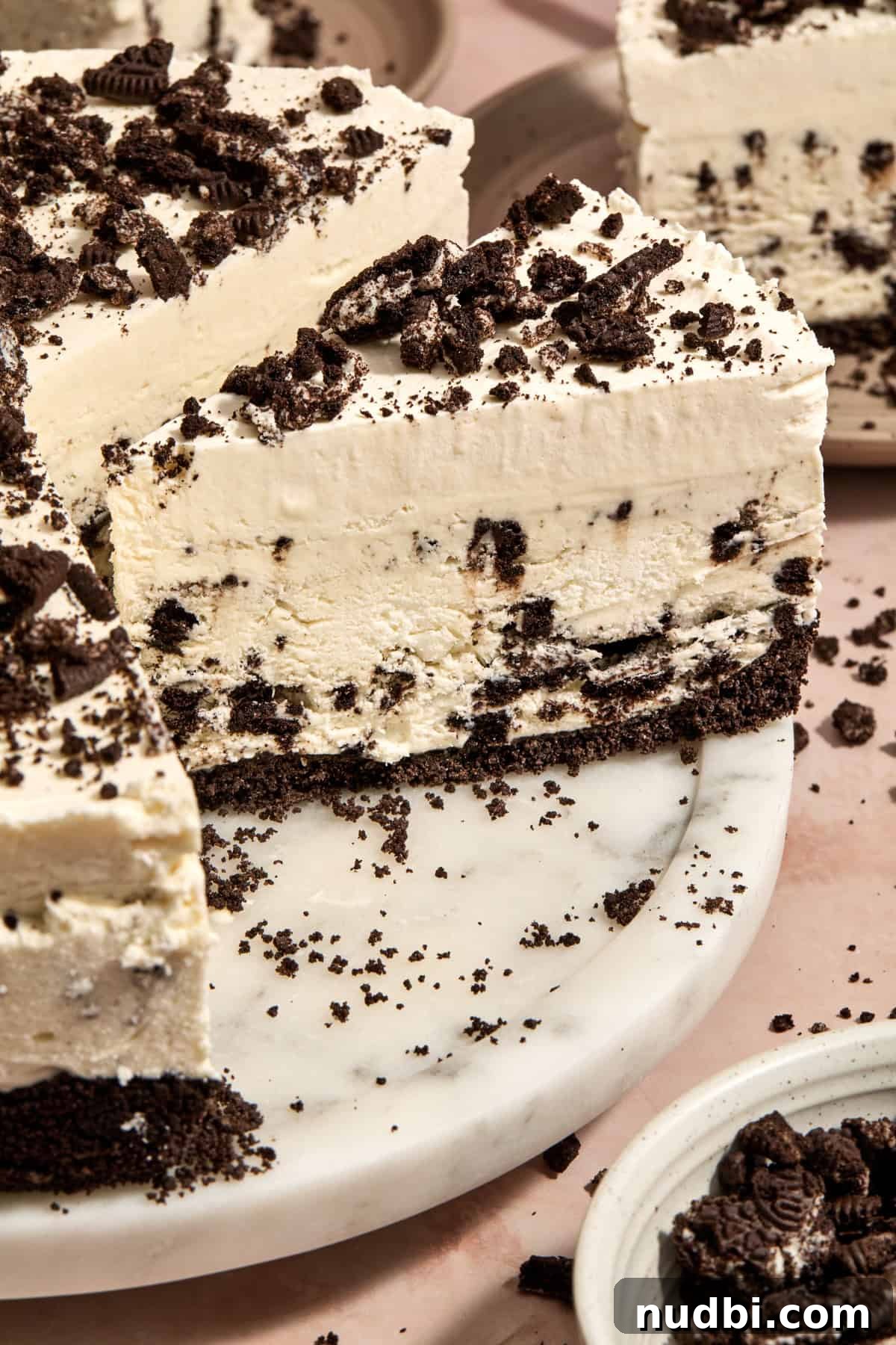 No-Bake Oreo Ice Cream Pie Recipe — Creamy Chocolate Sandwich Dessert 13 Ice cream pie on cake plate with whipped cream layer and crushed chocolate cookies on top.