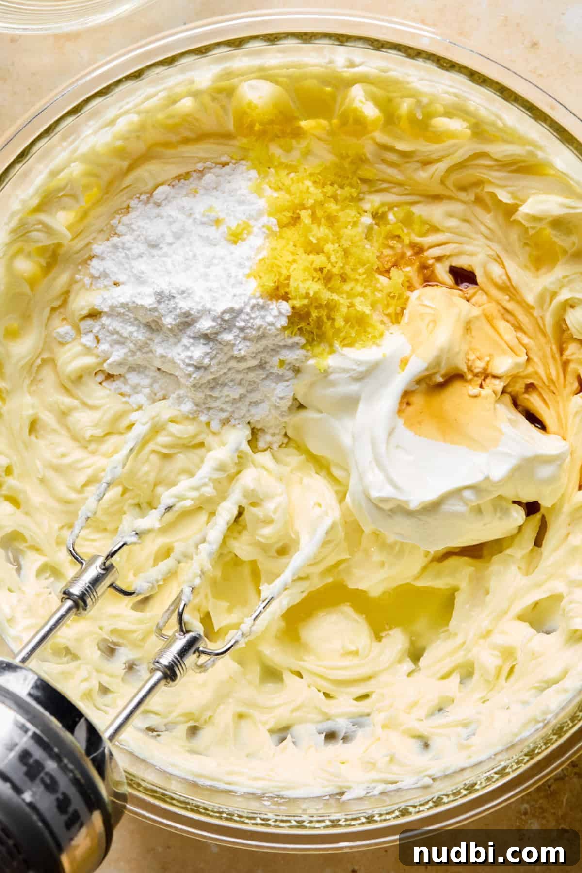 No-Bake Lemon Cheesecake Bars with Zesty Graham Crust 10 Sour cream, lemon zest, powdered sugar and other ingredients in glass mixing bowl with cream cheese mixture.