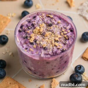 Creamy Blueberry Cheesecake Overnight Oats Recipe 13 Jar with blueberry cream cheese overnight oatmeal topped with graham crackers.