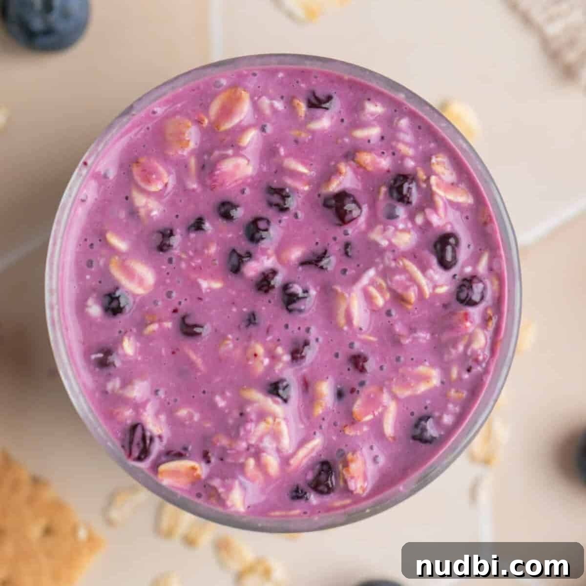 Creamy Blueberry Cheesecake Overnight Oats Recipe 7 Prepared overnight oatmeal with blueberries and cream cheese in glass cup.