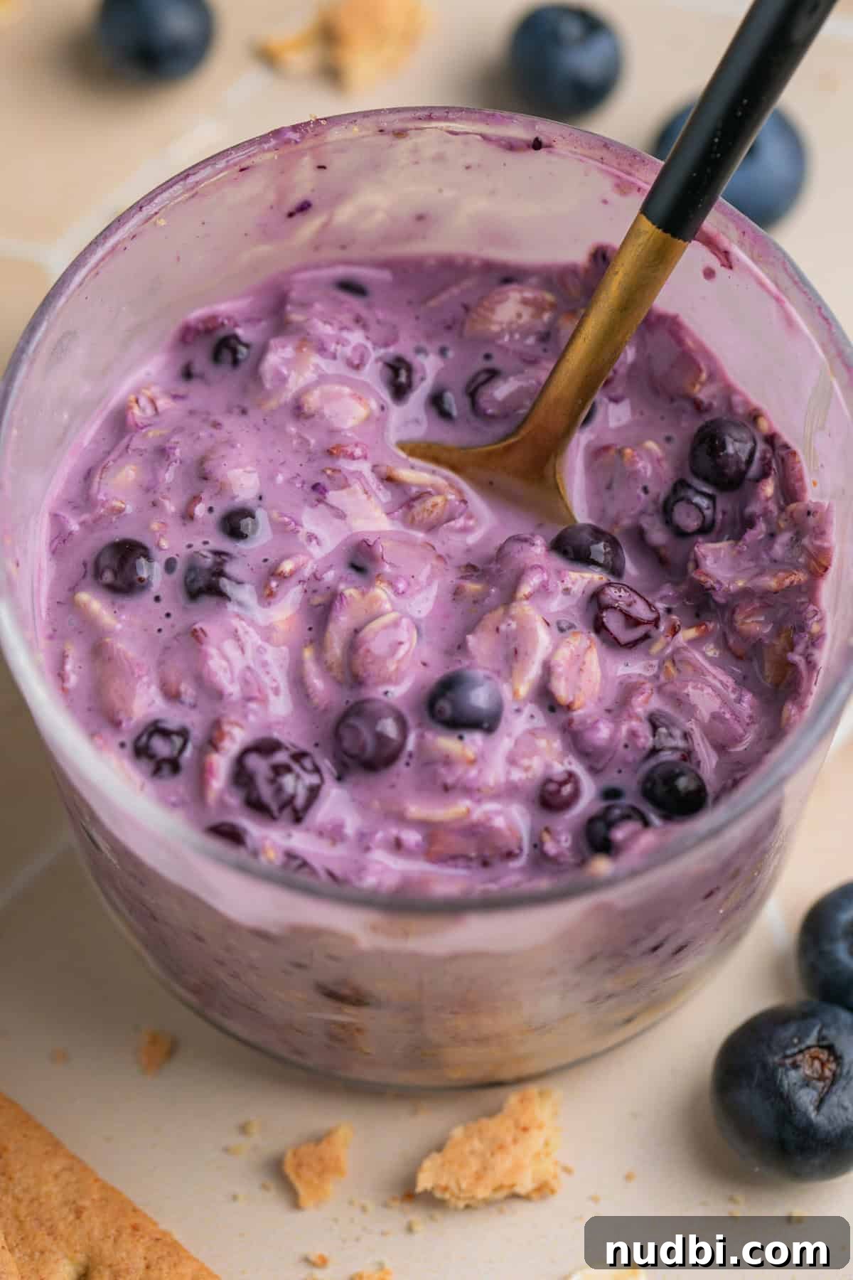 Creamy Blueberry Cheesecake Overnight Oats Recipe 8 Spoon scooping into cheesecake overnight oatmeal with blueberries.