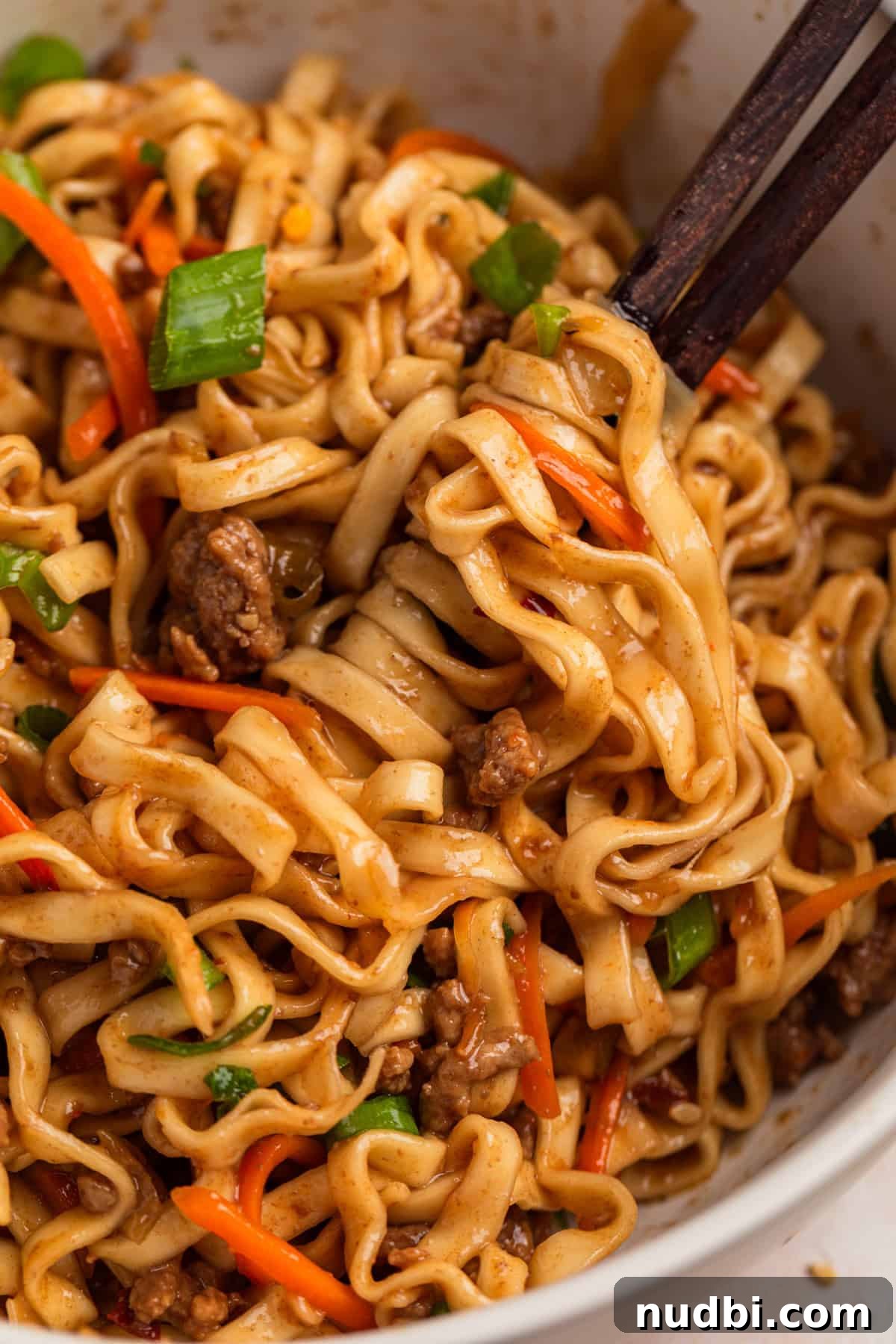 Savory Ground Beef Ramen Noodle Recipe 11 Beef noodles on chopsticks in bowl.