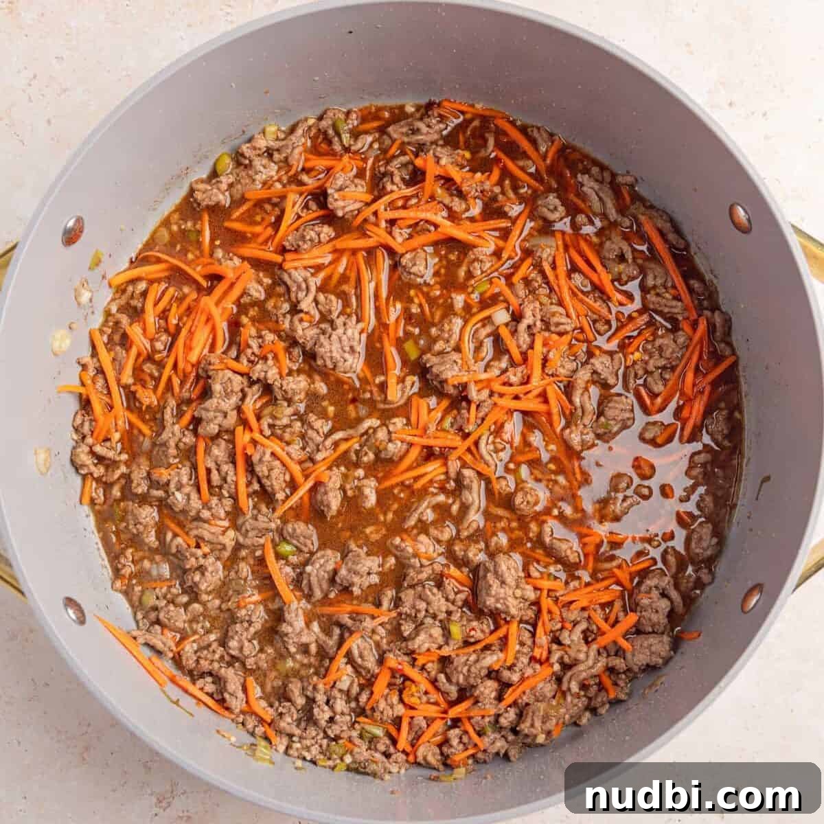 Savory Ground Beef Ramen Noodle Recipe 7 Browned ground beef with carrots and sauce added to pan.