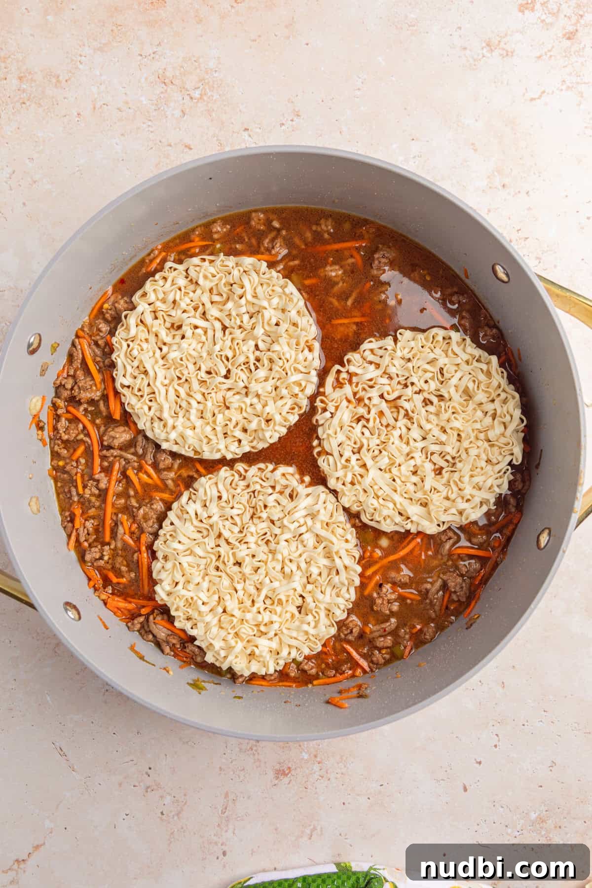 Savory Ground Beef Ramen Noodle Recipe 8 Ramen noodles added to skillet with beef and carrots.