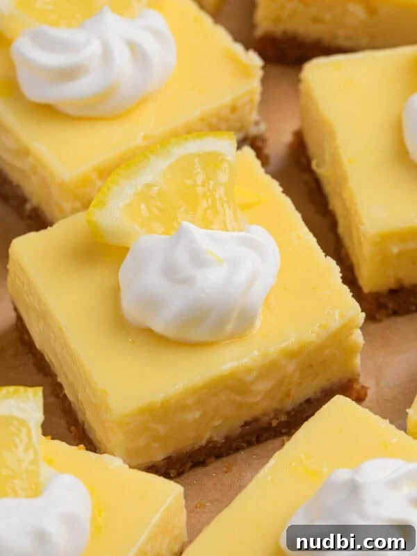 Sliced creamy lemon bars topped with dollop of whipped cream and lemon slice.
