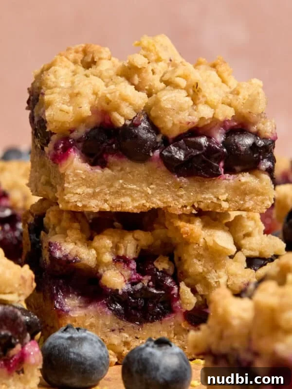 Stacked blueberry lemon bars with blueberries and other bars around it.