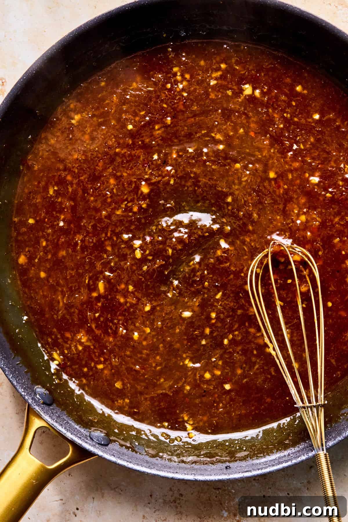 Crispy Spicy Orange Chicken with Tangy Sauce 11 Cooked spicy orange sauce in skillet with whisk.