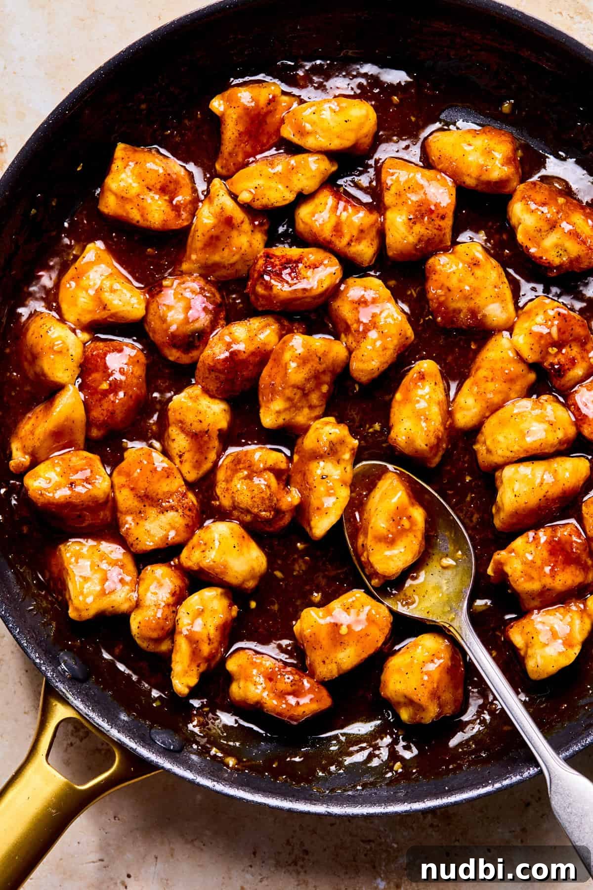 Crispy Spicy Orange Chicken with Tangy Sauce 12 Spicy orange chicken in pan coated with sauce.