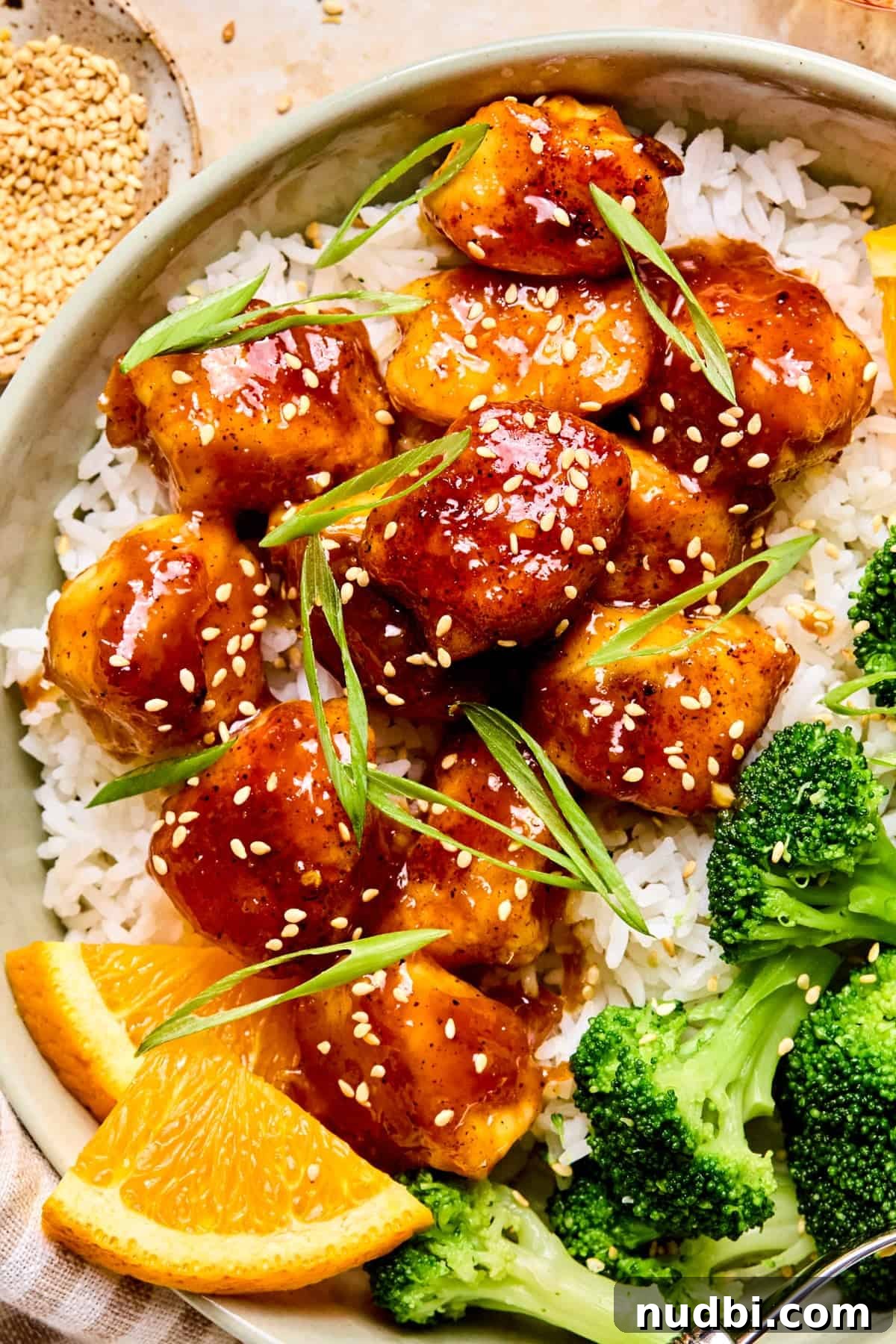 Crispy Spicy Orange Chicken with Tangy Sauce 13 Orange chicken over rice topped with scallions and sesame seeds.