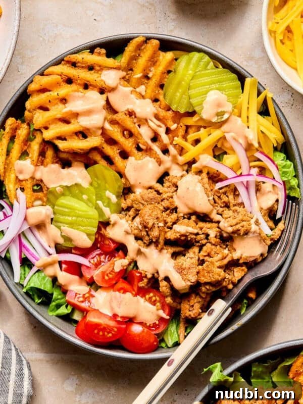 Bowl with ground turkey topped with burger sauce, waffle fries and other burger toppings.