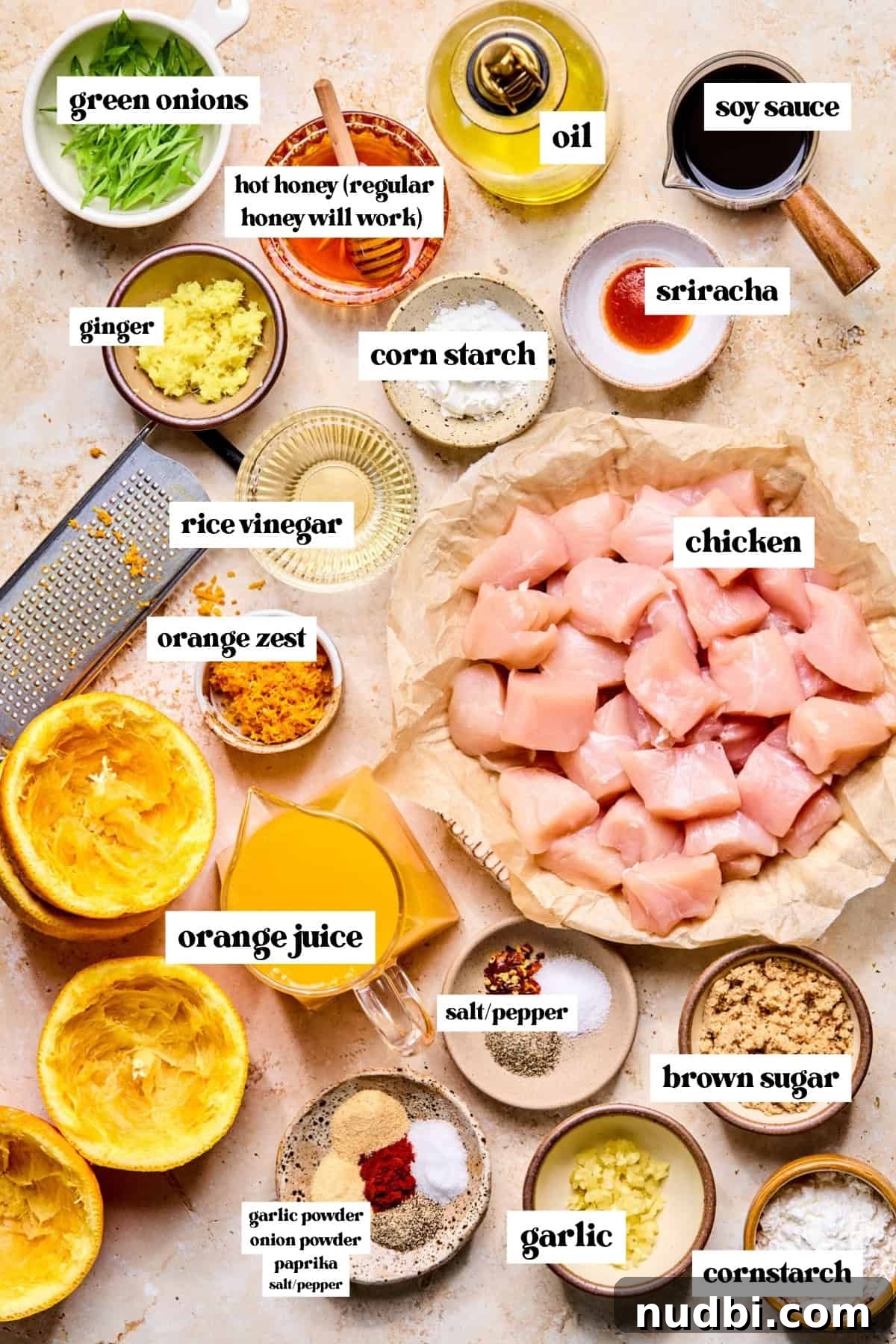 Crispy Spicy Orange Chicken with Tangy Sauce 4 Chicken pieces, green onion, garlic, ginger, soy sauce and other labeled ingredients on surface.