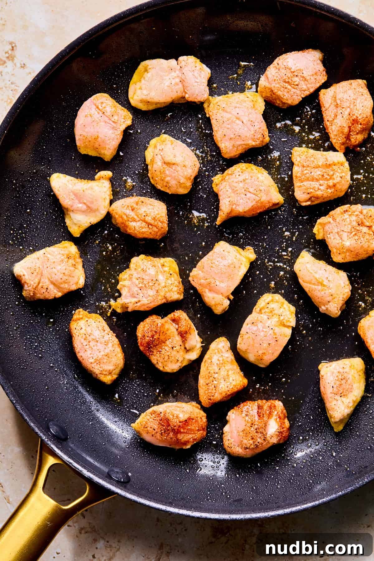 Crispy Spicy Orange Chicken with Tangy Sauce 8 Chicken pieces searing in skillet.