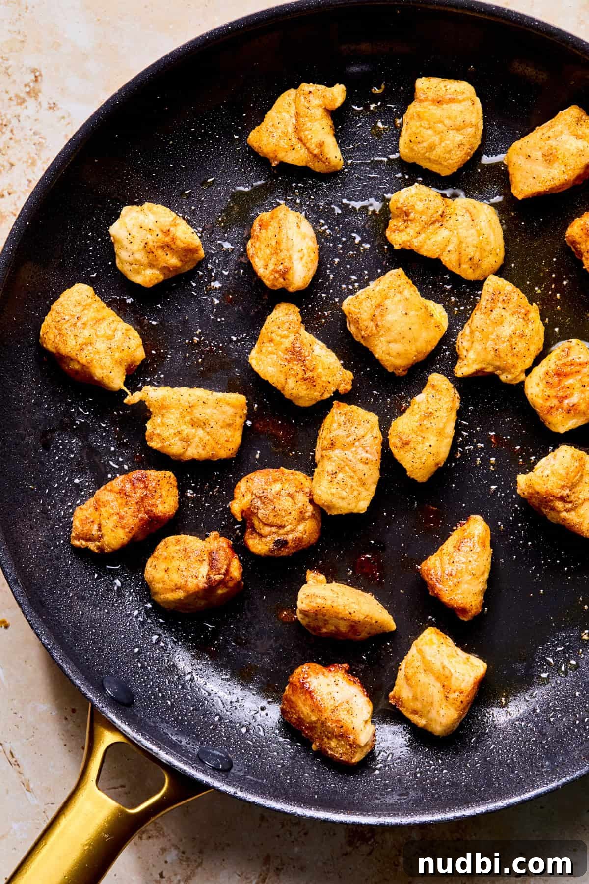 Crispy Spicy Orange Chicken with Tangy Sauce 9 Browned chicken bites in skillet.