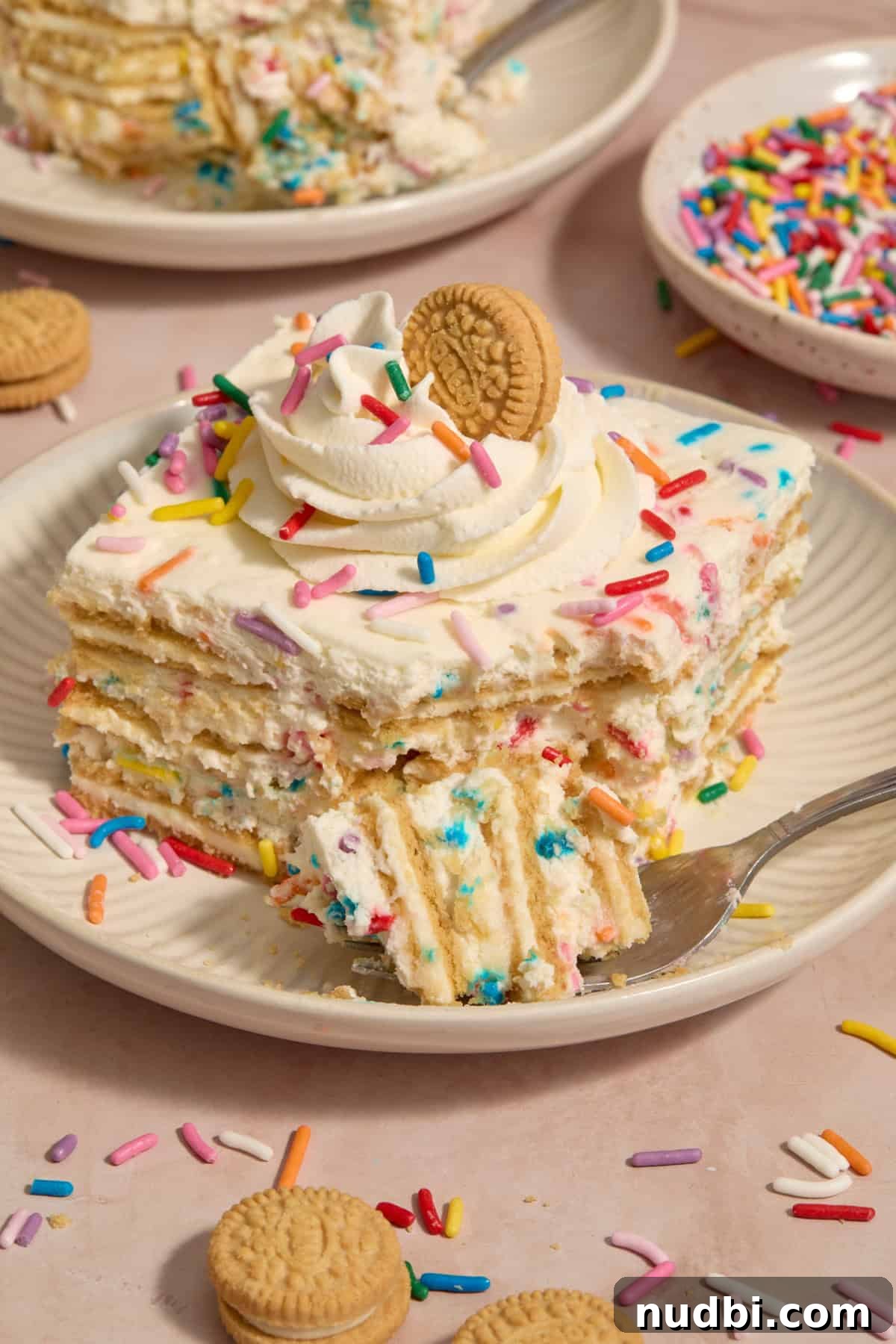 No-Bake Funfetti Icebox Cake Recipe with Whipped Frosting 15 Slice of funfetti layered cake with forkful propped beside the plate.