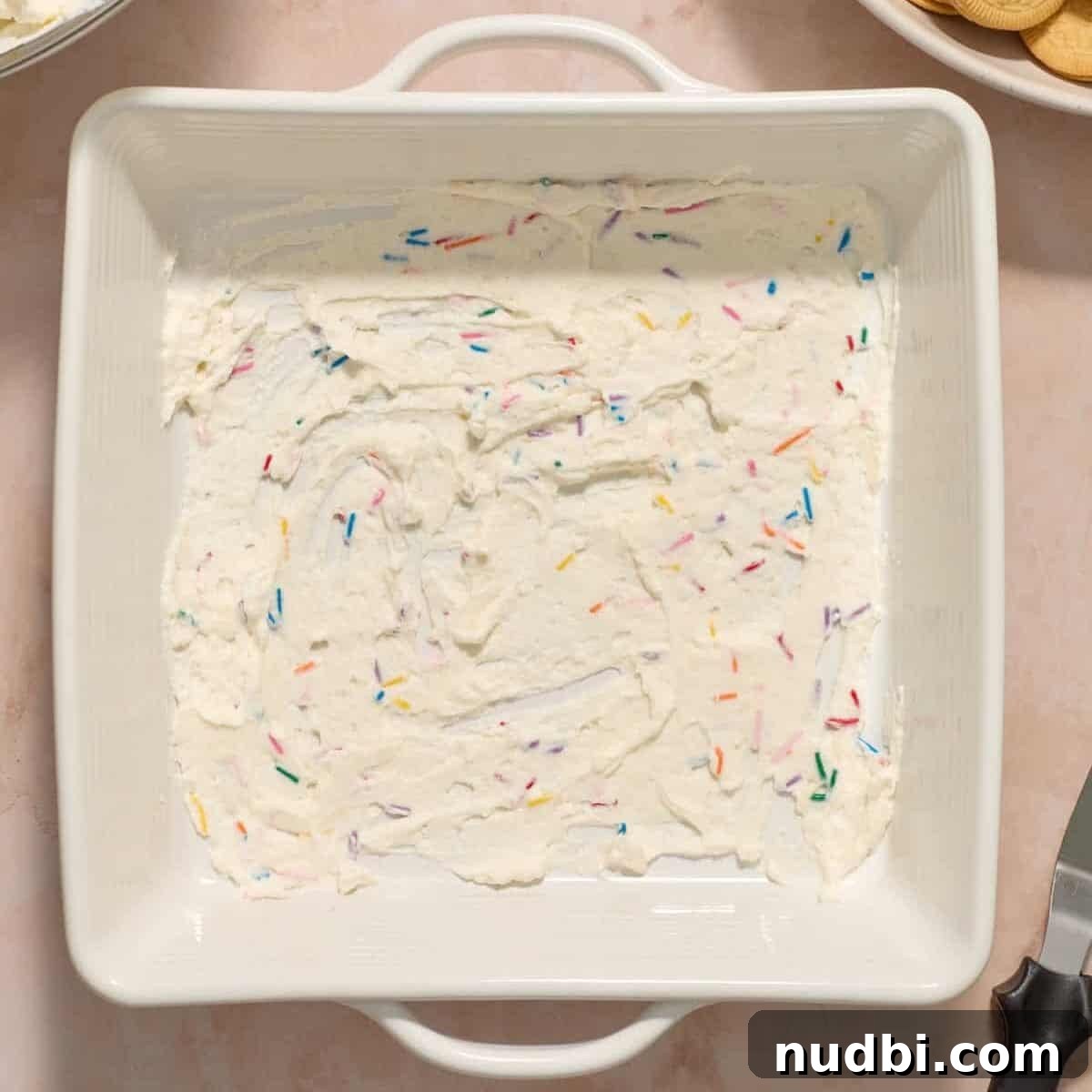 No-Bake Funfetti Icebox Cake Recipe with Whipped Frosting 9 Funfetti whipped cream mixture spread on the bottom of square pan.