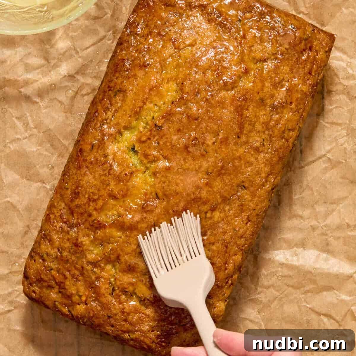 Lemon glaze brushed on top of baked loaf with pastry brush.