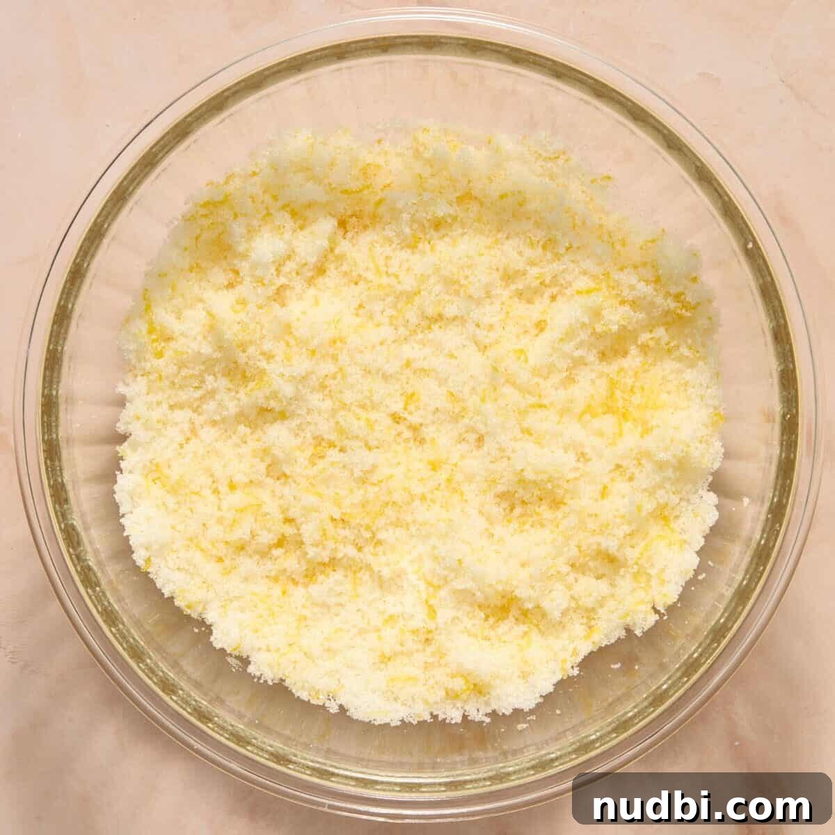 Lemon and sugar massaged together in glass mixing bowl.