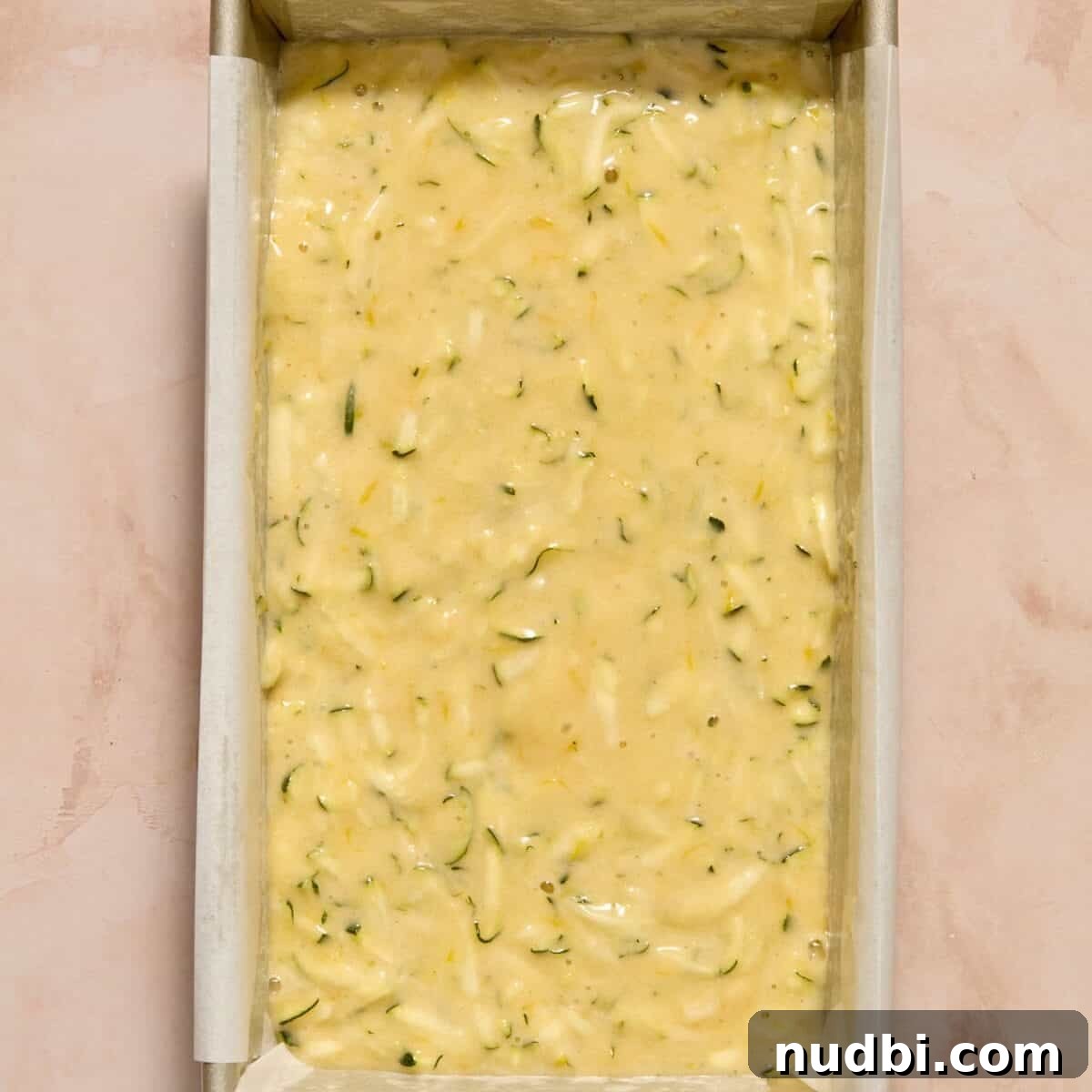 Lemon zucchini bread batter in parchment lined bread pan.